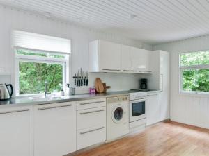 een keuken met witte kasten en een wasmachine bij Holiday Home Hilde - 1-7km from the sea in NE Jutland by Interhome in Sæby