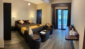 1 Schlafzimmer mit einem großen Bett und 2 Stühlen in der Unterkunft The Arbour Inn in Shillong