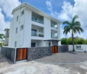 a white house with a palm tree in front of it at Serenity apartments in Trou aux Biches