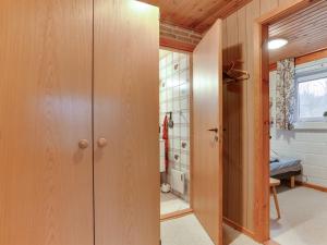 uma casa de banho com armários de madeira e uma cabina de duche ao nível do chão em Holiday Home Anemarie - 450m from the sea in NE Jutland by Interhome em Sæby