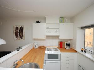 uma cozinha com armários brancos, um lavatório e um fogão em Apartment Runhild - 100m from the sea in NE Jutland by Interhome em Hals