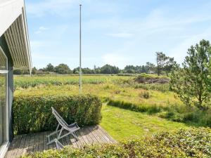 een bank op een veranda naast een veld bij Holiday Home Glum - 300m from the sea in NE Jutland by Interhome in Sæby