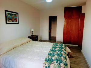 1 dormitorio con cama blanca y armario de madera en Tres Jolie en Guaymallén