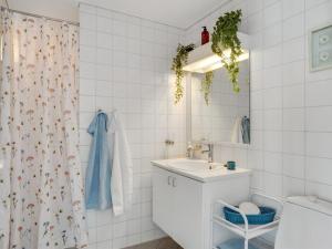 y baño blanco con lavabo y ducha. en Apartment Dafna - 100m from the sea in NE Jutland by Interhome, en Hals
