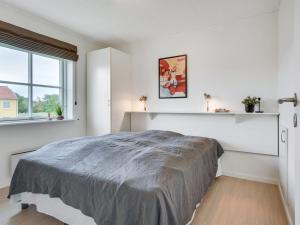 een witte slaapkamer met een groot bed en een raam bij Apartment Sipi - 100m from the sea in NE Jutland by Interhome in Hals