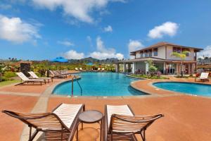 a swimming pool with chairs and a house at Pili Mai 6K in Koloa