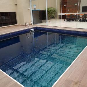 a swimming pool with a tile floor and a swimming pool at Hotel Victoria Villa Curitiba by Nacional Inn in Curitiba