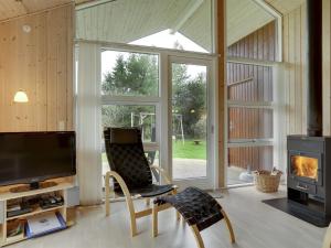 ein Wohnzimmer mit einem TV, einem Stuhl und einem Kamin in der Unterkunft Holiday Home Thorketil - 1-1km from the sea in NE Jutland by Interhome in Hals