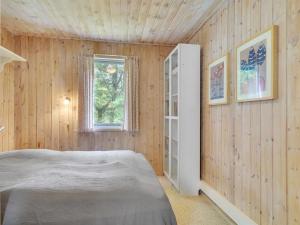 1 dormitorio con paneles de madera, 1 cama y ventana en Holiday Home Ane - 1-7km from the sea in NE Jutland by Interhome, en Hals