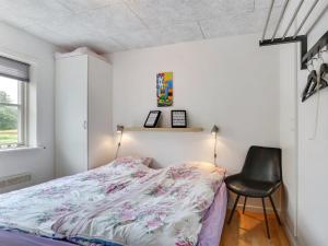 um quarto com uma cama e uma cadeira preta em Apartment Amaryllis - 100m from the sea in NE Jutland by Interhome em Hals