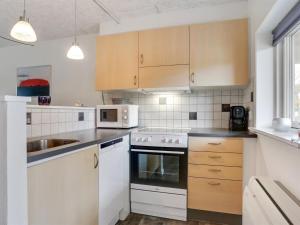 una cocina con electrodomésticos blancos y armarios de madera en Apartment Amaryllis - 100m from the sea in NE Jutland by Interhome en Hals