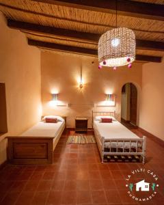 sypialnia z 2 łóżkami i żyrandolem w obiekcie La Vilti casa de Purmamarca w mieście Purmamarca