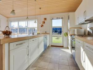 een keuken met witte kasten en een groot raam bij Holiday Home Bertram - 1-9km from the sea in NE Jutland by Interhome in Hals