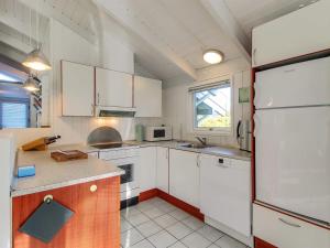 een keuken met witte kasten en een koelkast bij Holiday Home Clari - 500m from the sea in NE Jutland by Interhome in Hals