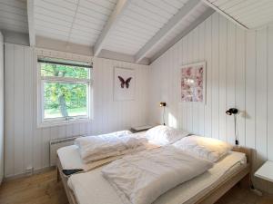 een slaapkamer met een bed met witte lakens en een raam bij Holiday Home Clari - 500m from the sea in NE Jutland by Interhome in Hals