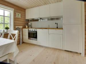 eine Küche mit weißen Schränken und Holzböden in der Unterkunft Holiday Home Gaetana - 1-6km from the sea in NE Jutland by Interhome in Hals