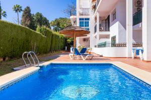 een zwembad met 2 stoelen en een parasol naast een huis bij Paloma's Cozy Beach Flat in Torremolinos