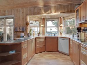 une grande cuisine avec des murs en bois et des placards en bois dans l'établissement Holiday Home Annestine - 50m from the sea in NE Jutland by Interhome, à Hals