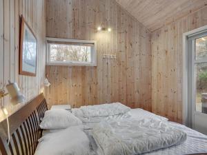 - une chambre avec un lit dans un mur en bois dans l'établissement Holiday Home Annestine - 50m from the sea in NE Jutland by Interhome, à Hals