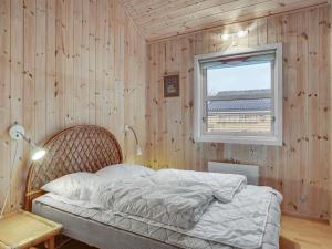- une chambre avec des murs en bois et un lit avec une fenêtre dans l'établissement Holiday Home Annestine - 50m from the sea in NE Jutland by Interhome, à Hals