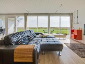 uma sala de estar com um sofá de couro e janelas grandes em Holiday Home Helja - 125m from the sea in NE Jutland by Interhome em Hals
