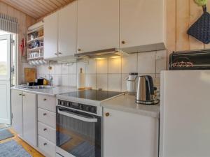 a kitchen with white cabinets and a stove and a refrigerator at Holiday Home Adi - 75m from the sea in NW Jutland by Interhome in Løkken