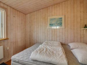 a bedroom with a bed in a room with wooden walls at Holiday Home Adi - 75m from the sea in NW Jutland by Interhome in Løkken