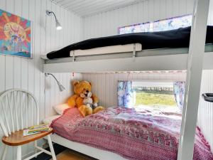 a teddy bear sitting on a bed in a bedroom at Holiday Home Guthrik - 900m from the sea by Interhome in Hadsund