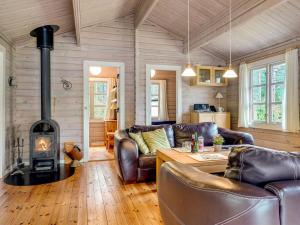 uma sala de estar com mobiliário de couro e um fogão a lenha em Holiday Home Uuno - 1-2km from the sea in NE Jutland by Interhome em Hadsund