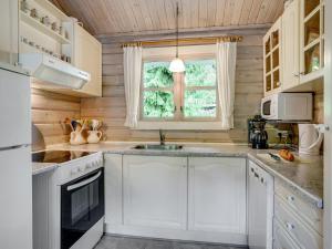 uma cozinha com armários brancos e uma janela em Holiday Home Uuno - 1-2km from the sea in NE Jutland by Interhome em Hadsund