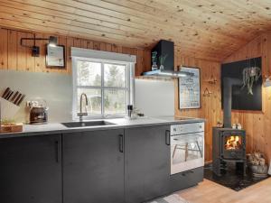 a kitchen with a stove and a sink and a fireplace at Holiday Home Imma - from the sea in NE Jutland by Interhome in Hals