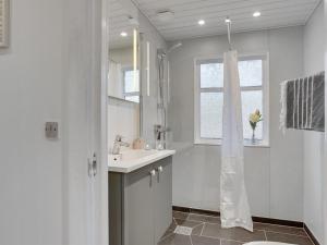 La salle de bains blanche est pourvue d'un lavabo et d'une fenêtre. dans l'établissement Holiday Home Marise - from the sea in NE Jutland by Interhome, à Hals