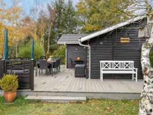einen schwarzen Schuppen mit einer Holzterrasse mit einem Tisch und Stühlen in der Unterkunft Holiday Home Tadej - from the sea in NE Jutland by Interhome in Hals