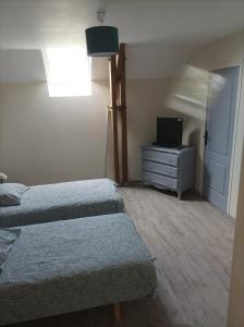 1 dormitorio con 2 camas y un tocador con TV en Gîte T'ché Dédée, en La Cambe