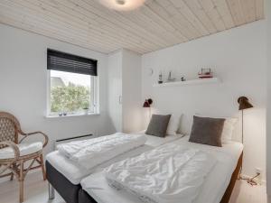 um quarto branco com uma cama e uma cadeira em Holiday Home Kerttuli - 800m from the sea in NE Jutland by Interhome em Hadsund