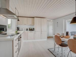 uma cozinha com armários brancos e uma mesa com cadeiras em Holiday Home Kerttuli - 800m from the sea in NE Jutland by Interhome em Hadsund