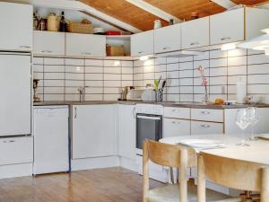 a kitchen with white appliances and a table at Holiday Home Herdina - 4km from the sea in NW Jutland by Interhome in Brovst