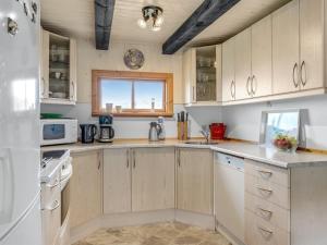 a kitchen with white cabinets and a window at Holiday Home Marite - 200m from the sea in NW Jutland by Interhome in Pandrup