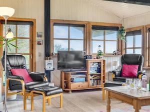 a living room with two chairs and a television at Holiday Home Marite - 200m from the sea in NW Jutland by Interhome in Pandrup