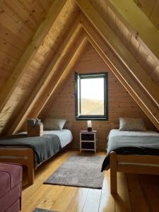 two beds in a attic room with a window at Brvnare Puljci in Nova Varoš
