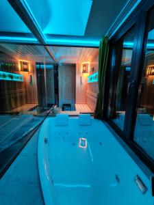 eine Badewanne in der Mitte eines Zimmers mit blauen Lichtern in der Unterkunft Smart Luxury Penthouse Suites - Private Sauna, Hot-Tub, Home Cinema at the best Location in Skopje in Skopje