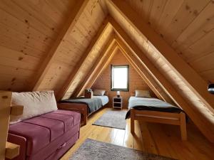 um quarto no sótão com 2 camas e um sofá em Brvnare Puljci em Nova Varoš