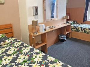 a room with two beds and a desk with a mirror at Hayward Hotel in Blackpool