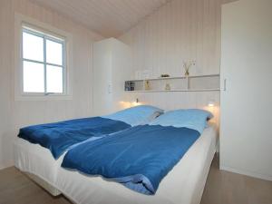 ein Schlafzimmer mit einem großen Bett mit blauer Bettwäsche in der Unterkunft Holiday Home Driss - all inclusive - 500m from the sea by Interhome in Pandrup