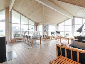 ein Wohnzimmer mit einem Tisch, Stühlen und Fenstern in der Unterkunft Holiday Home Fanija - 200m from the sea in NW Jutland by Interhome in Hjørring