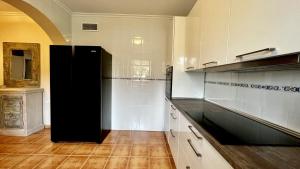 eine Küche mit weißen Schränken und einem schwarzen Kühlschrank in der Unterkunft Roca de Leones by United Renters in El Campello