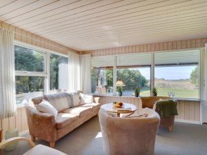 un soggiorno con divano, tavolo e finestre di Holiday Home Josefiina - 450m to the inlet in The Liim Fiord by Interhome a Løgsted