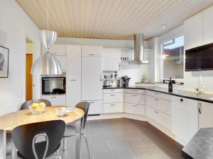 a kitchen with white cabinets and a wooden table at Holiday Home Sirja - 250m from the sea in NE Jutland by Interhome in Hadsund