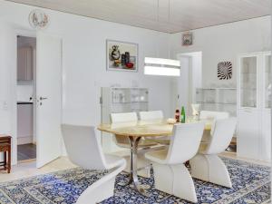 a dining room with a wooden table and white chairs at Holiday Home Sirja - 250m from the sea in NE Jutland by Interhome in Hadsund