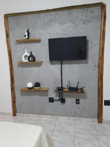 a room with a television on a wall with shelves at Apartamento novo perto da praia e shoppings in Vila Velha